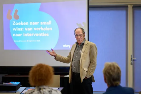 Spreker licht een dia toe met de tekst 'Zoeken naar small wins: van verhalen naar interventies'